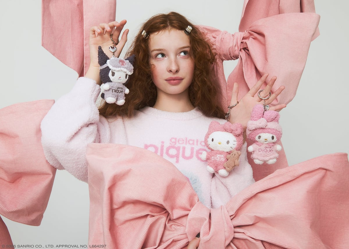 ピンクのルームウェアを着たモデルが、クロミ・ハローキティ・マイメロディのぬいぐるみチャームを手に持っている写真